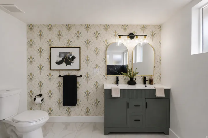 Dual sink vanity with matte black fixtures, gold-framed arched mirrors, and a black marble-look backsplash