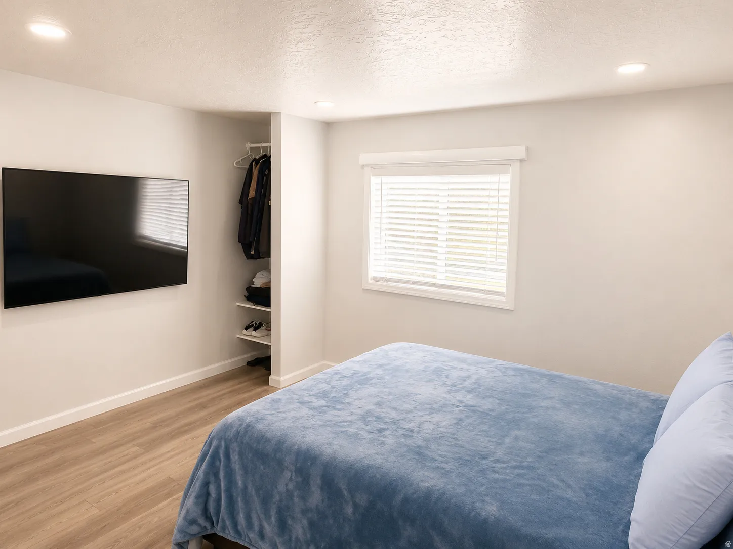 Bright interior space with wood-finish flooring, recessed lighting, and a built-in open closet with shelving