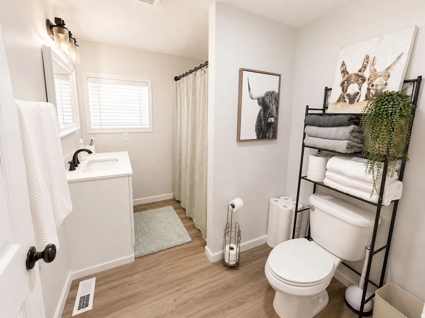 Bathroom featuring wood-finish flooring, a white vanity with a dark bronze faucet, and a window with blinds