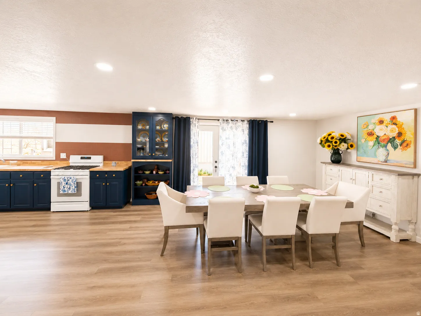 Open-concept living space featuring wood-finish flooring, a kitchen with blue cabinetry and wood-finish countertops, and recessed lighting