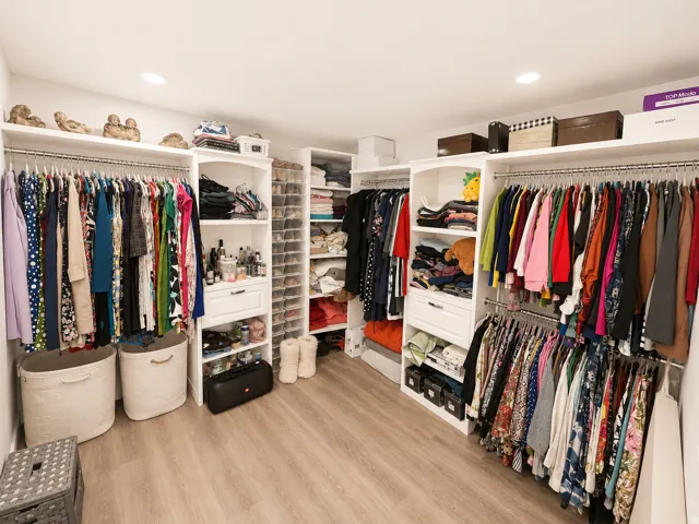 Custom closet system featuring wood-finish flooring, recessed lighting, multiple hanging rods, integrated shelving, and dedicated shoe storage