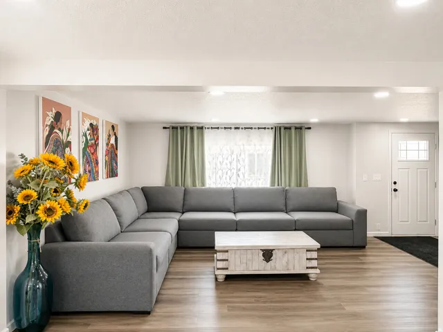 Living area featuring wood-finish flooring, recessed lighting, and a window with sheer and solid curtains