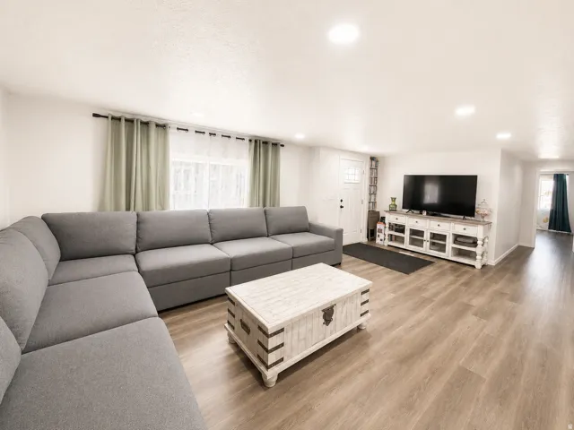 Spacious interior featuring light wood-finish flooring, recessed lighting, white walls, and a white paneled entry door