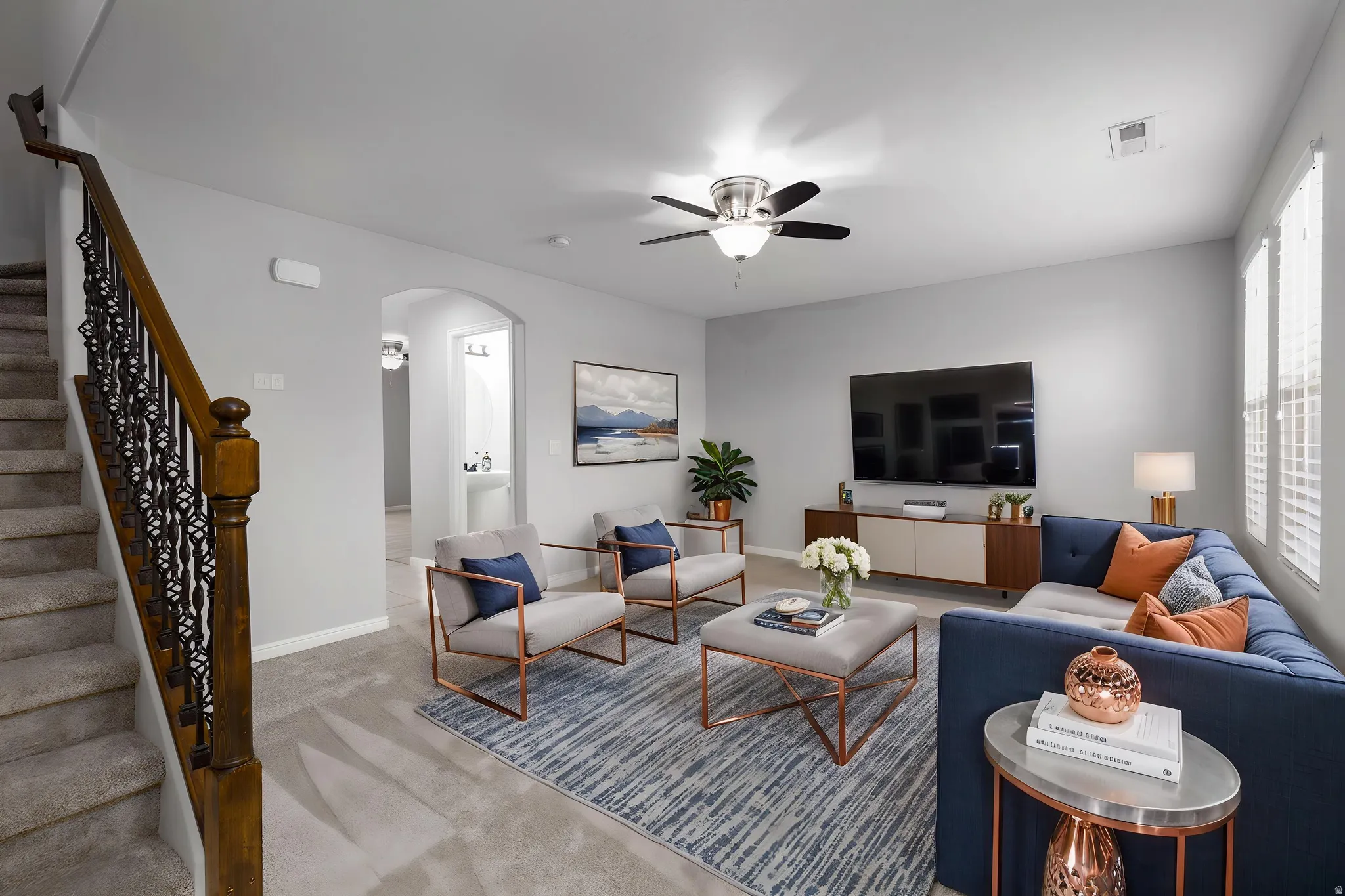 Living room with light colored carpet, arched walkways, and ceiling fan, virtual staging