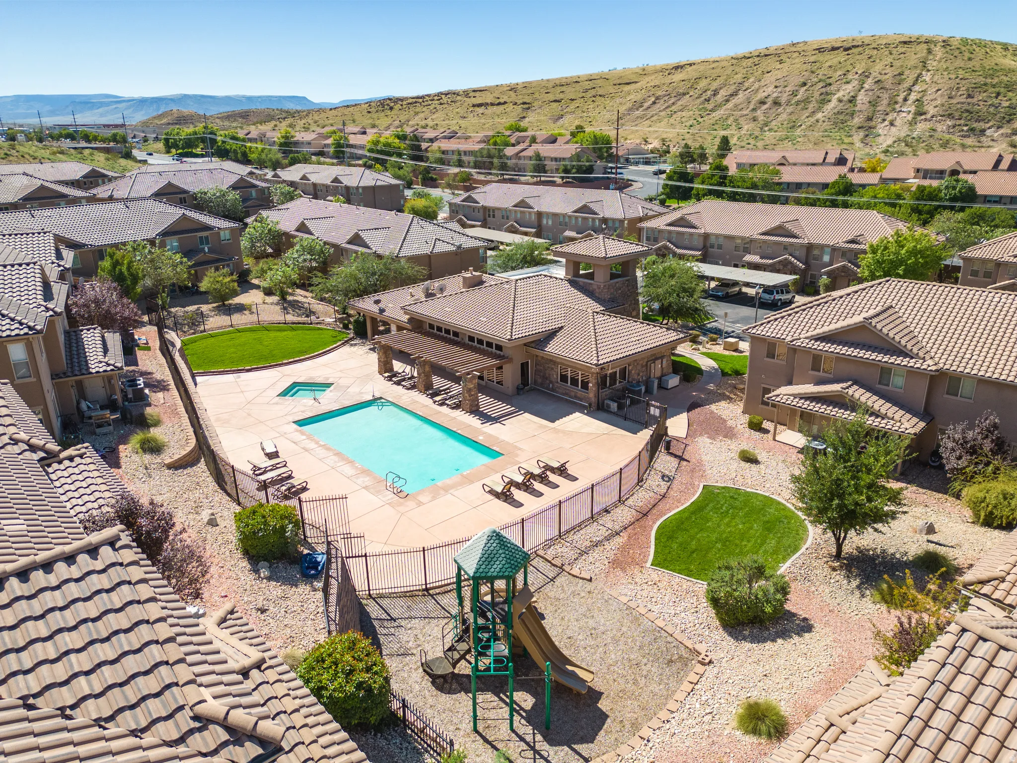 Aerial view of residential area with a pool, spa, playground, picnic areas and a mountainous background