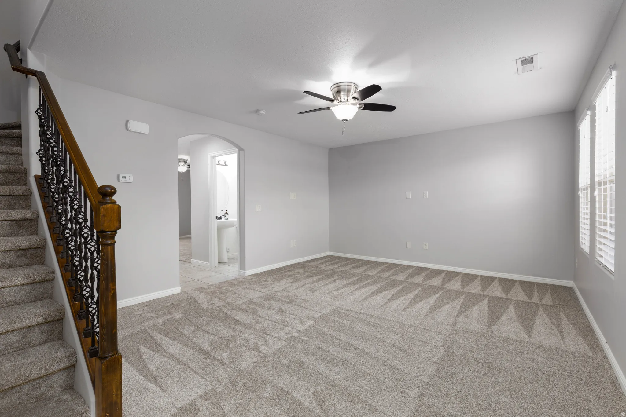 Living room with arched walkways, a ceiling fan, and light carpet