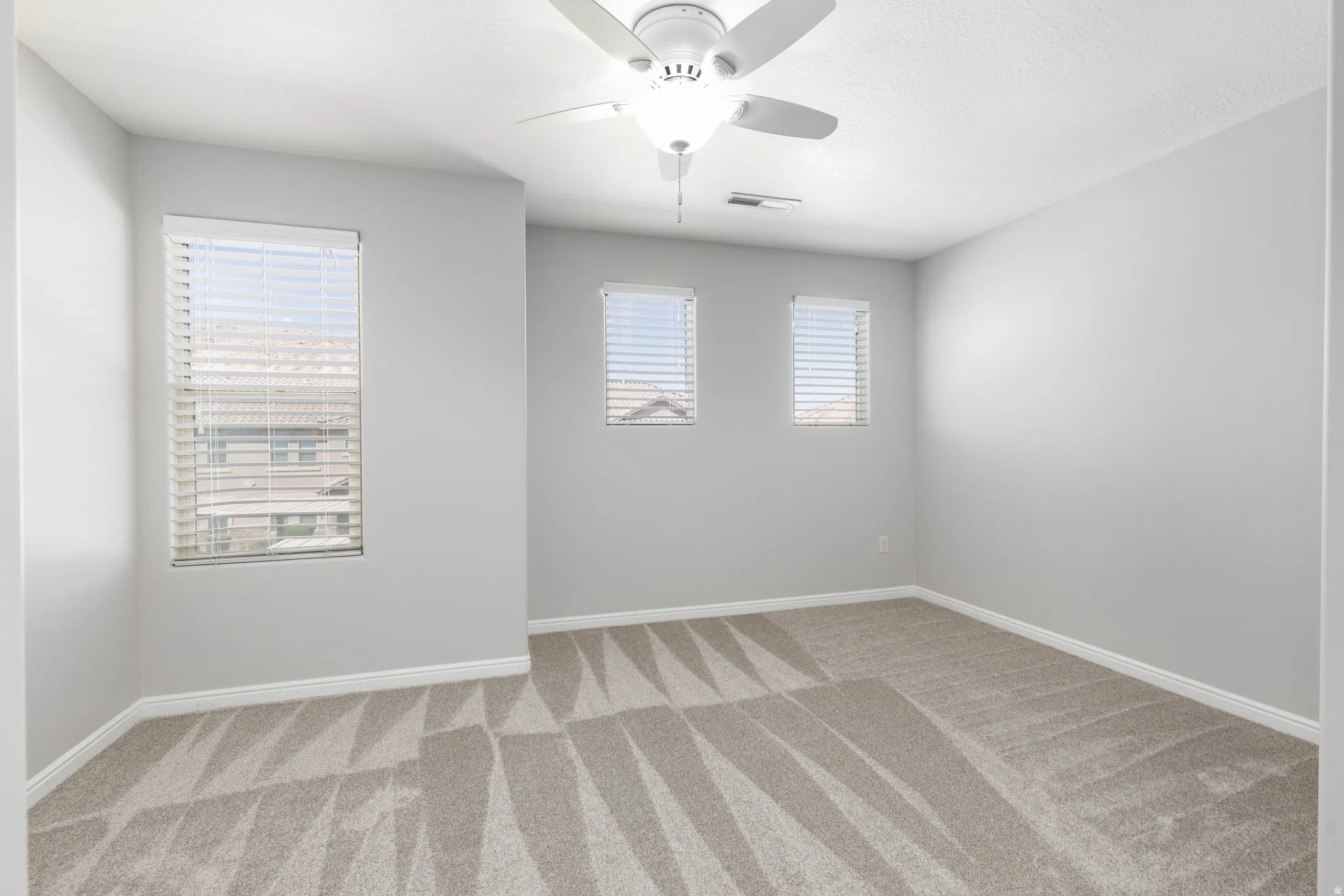 Primary suite with a ceiling fan and light carpet
