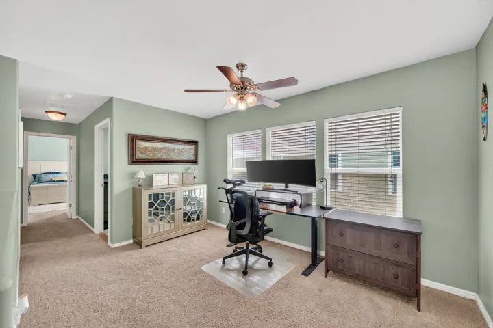 Home office featuring ceiling fan and light carpet