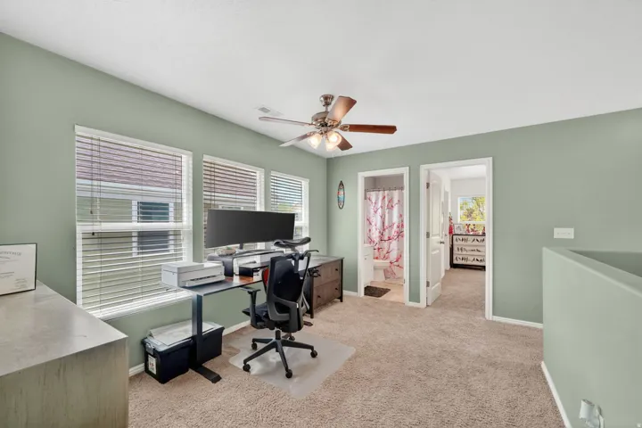 Office area featuring ceiling fan, light colored carpet, and plenty of natural light