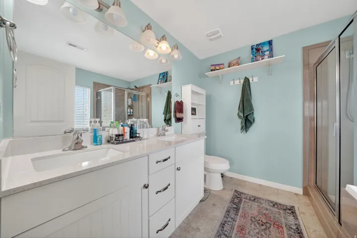 Full bath featuring double vanity and a stall shower