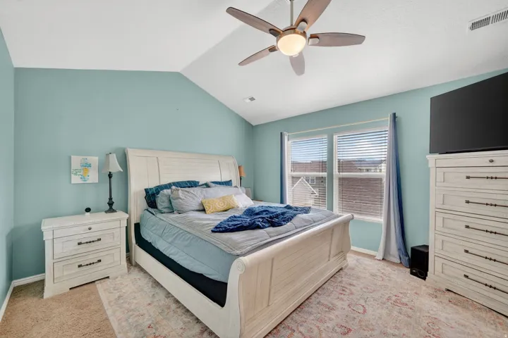 Bedroom with light colored carpet, a ceiling fan, and lofted ceiling