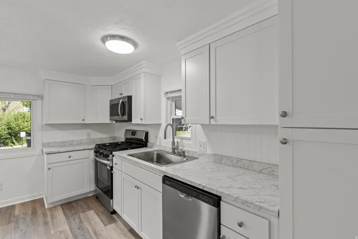 Kitchen featuring stainless steel appliances, light countertops, white cabinetry, light wood finished floors, and a textured ceiling