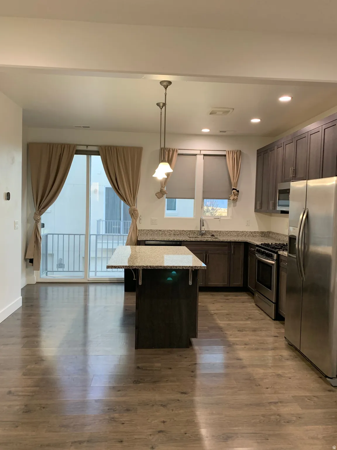 Kitchen featuring stainless steel appliances, light stone countertops, and plenty of natural light