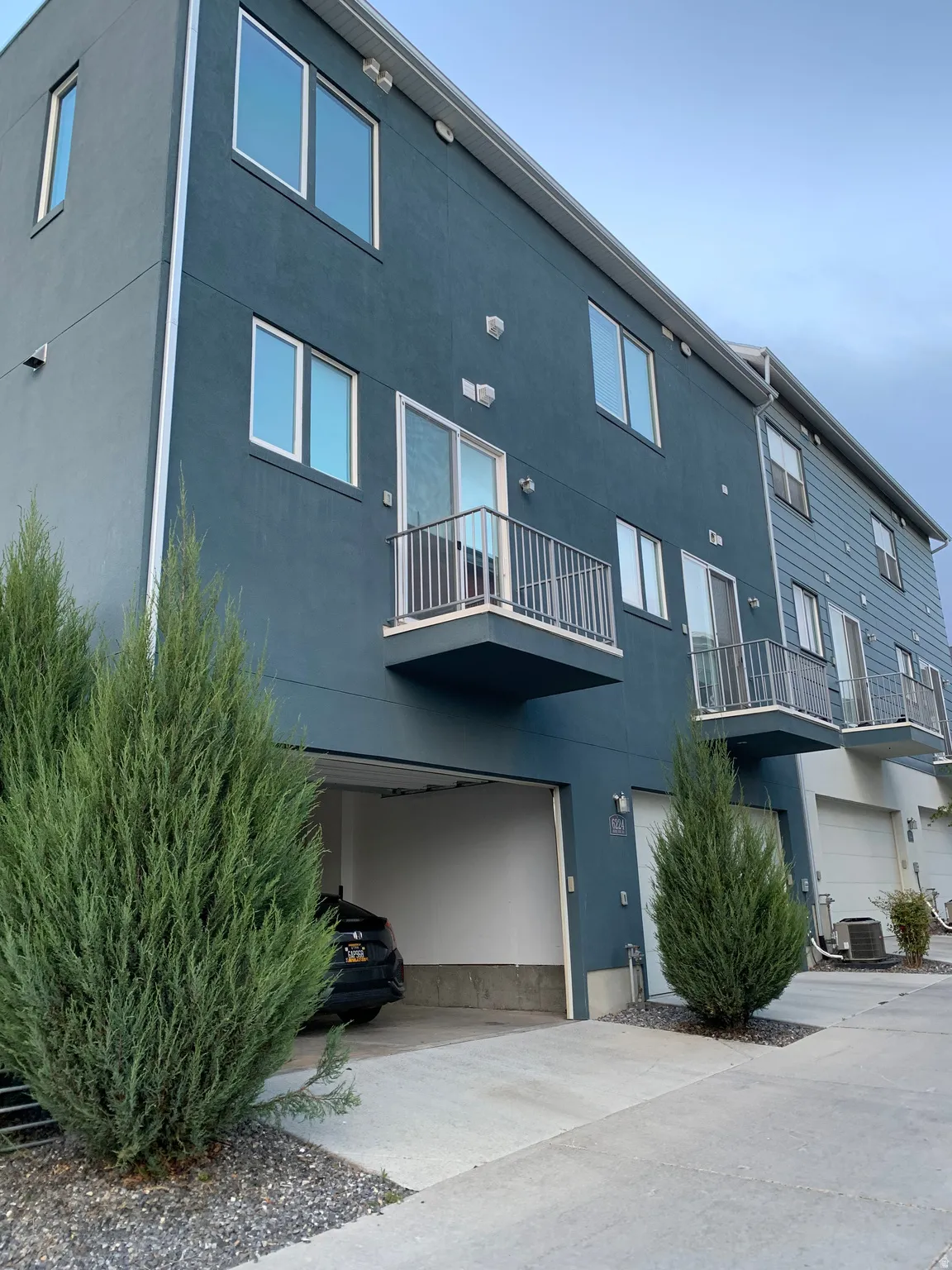 View of apartment building / complex with a garage and concrete driveway