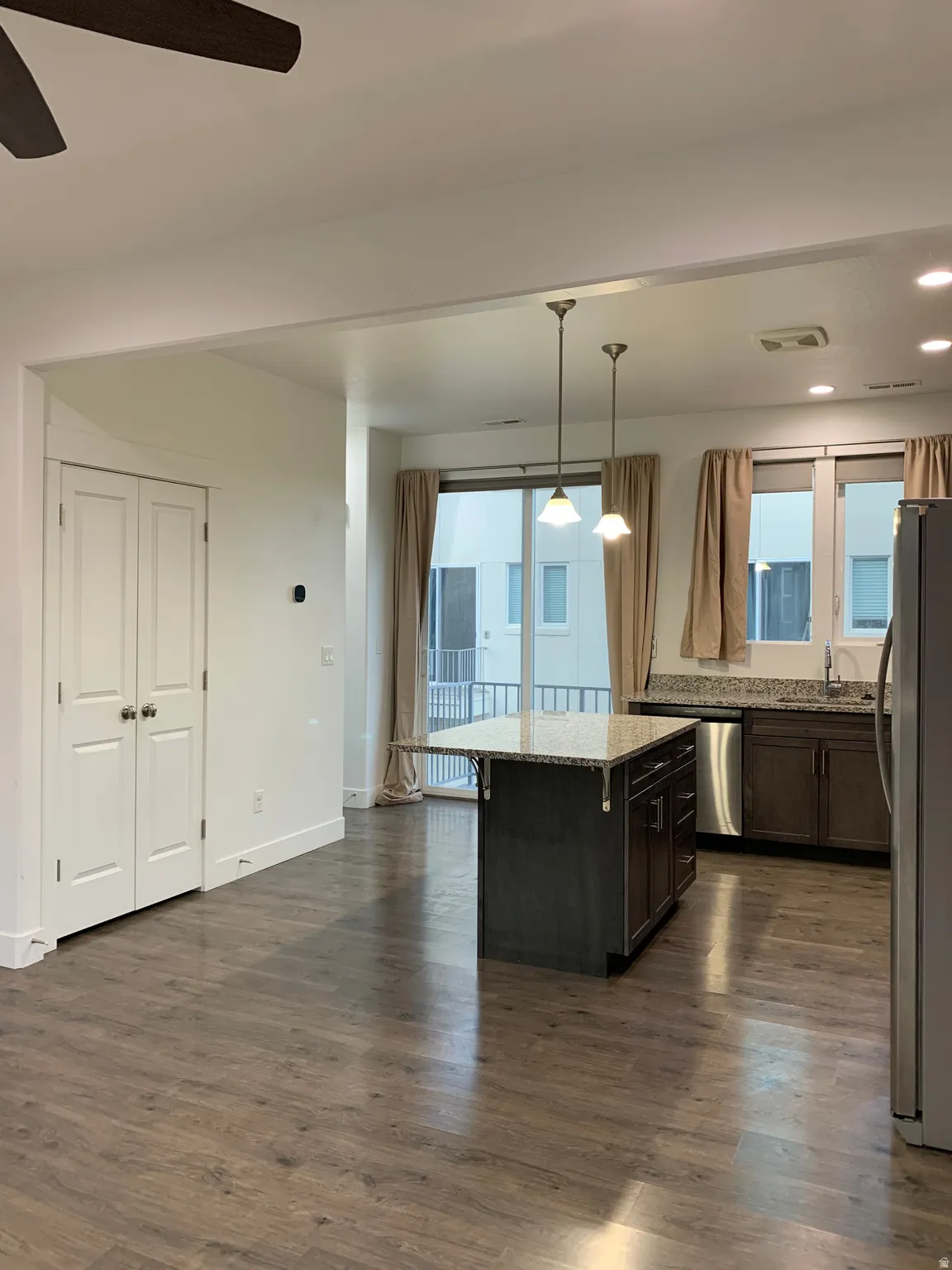 Kitchen with decorative light fixtures, granite countertops, ceiling fan, stainless steel appliances, pantry, and healthy amount of natural light