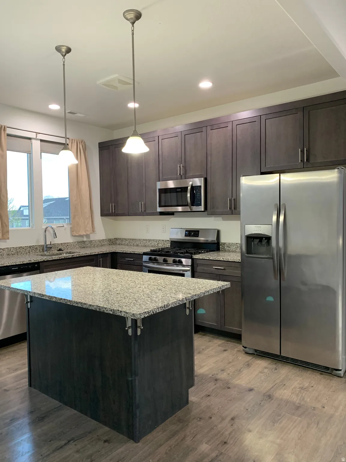 Kitchen featuring stainless steel appliances, gas stove, granite countertops, island