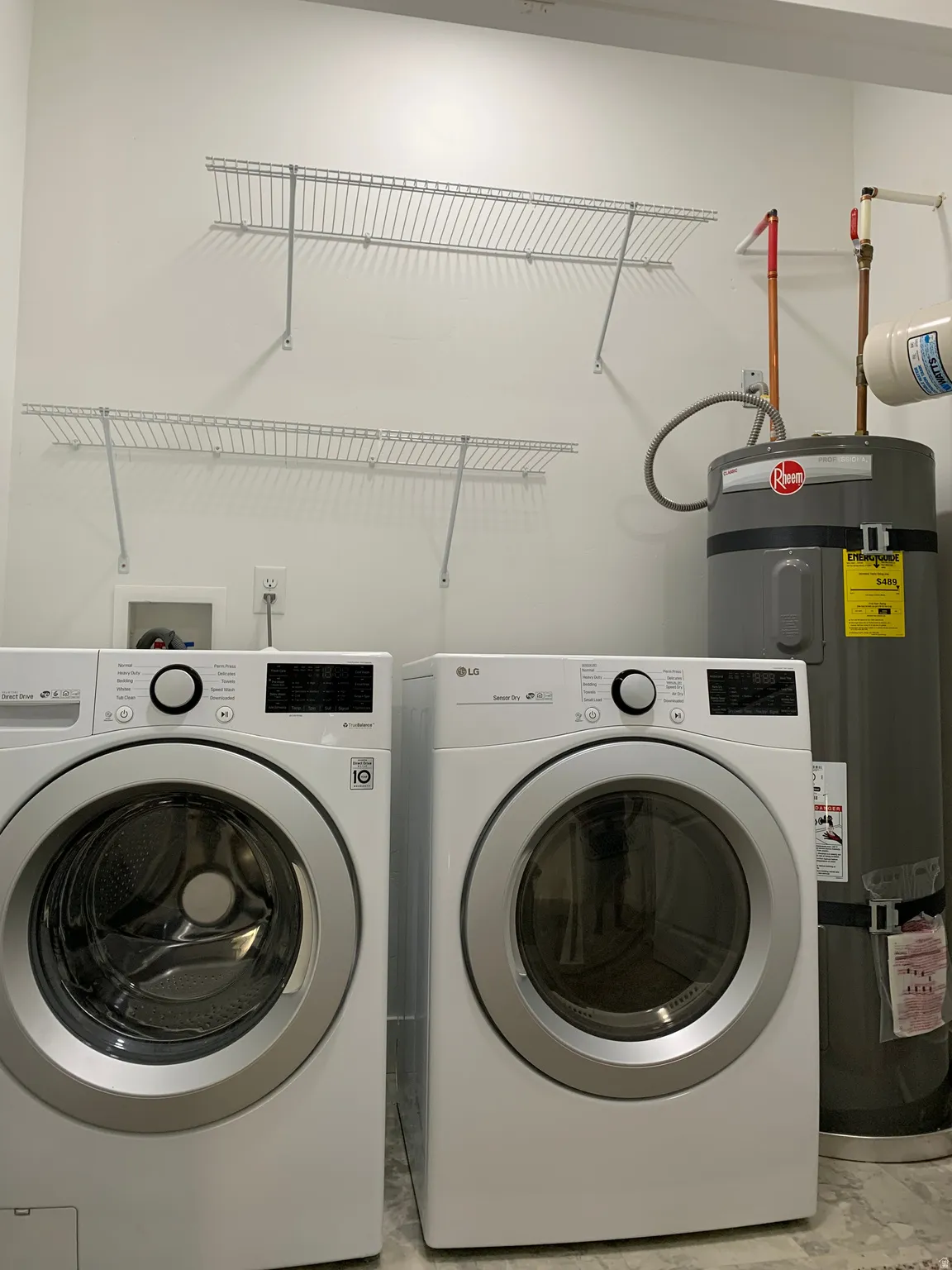 Laundry room with strapped water heater and washer and clothes dryer