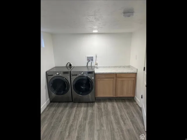Laundry room with cabinet space, dark wood-type flooring, and washer and clothes dryer
