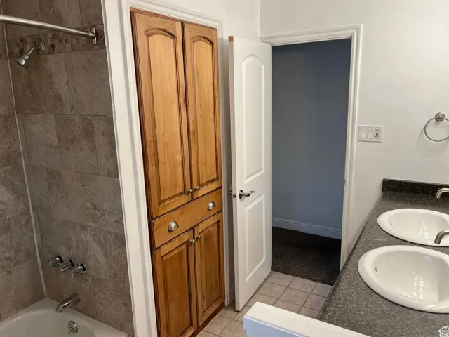 Full bath featuring a closet, double vanity, bathing tub / shower combination, and light tile patterned floors