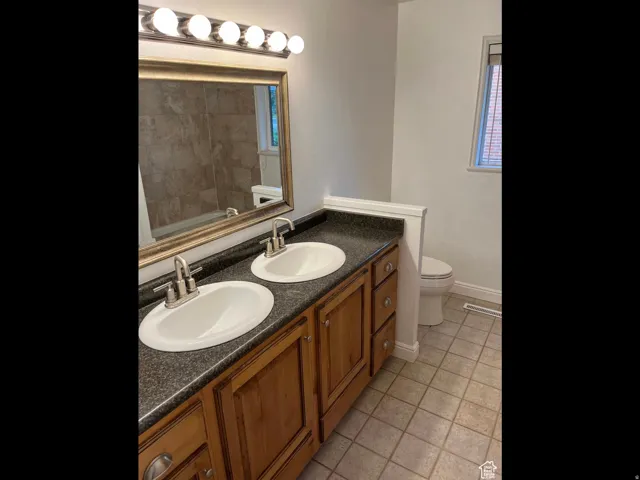 Full bath with double vanity, light tile patterned flooring, and a bath