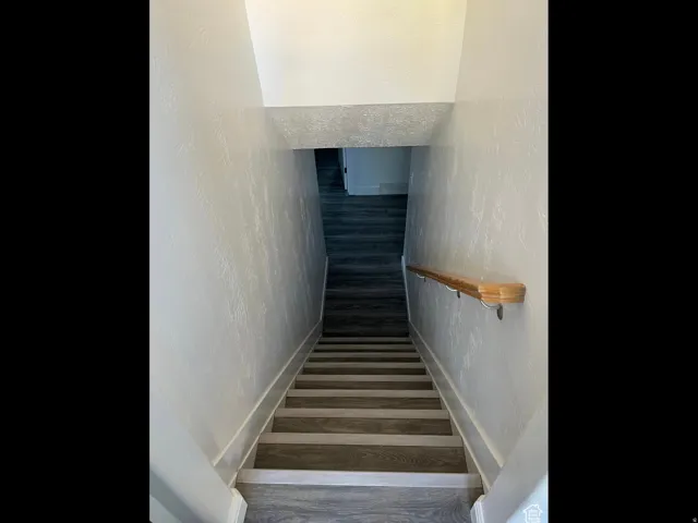 Staircase featuring a textured wall and wood finished floors