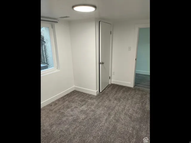 Spare room featuring baseboards and dark colored carpet