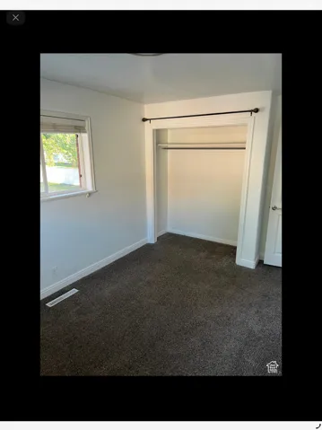 Unfurnished bedroom featuring dark colored carpet and a closet