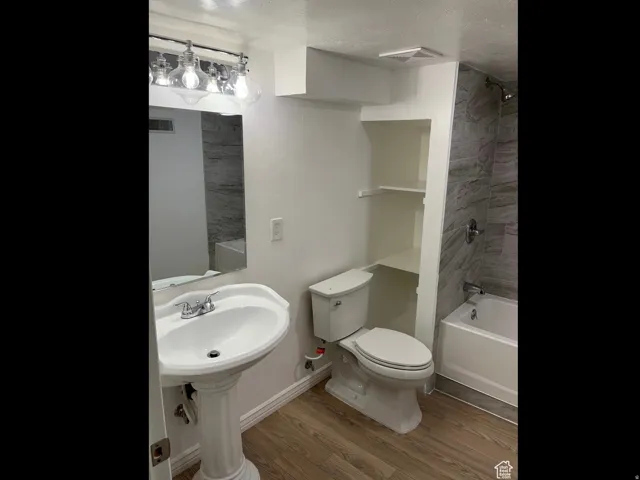 Full bath with light wood-style floors, shower / washtub combination, and a textured ceiling
