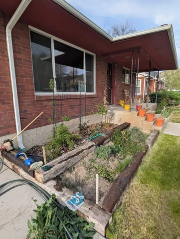 View of front of property featuring a porch, brick siding, and a garden