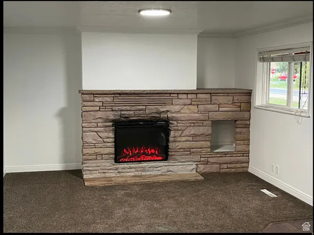 Detailed view of ornamental molding, carpet flooring, and a stone fireplace