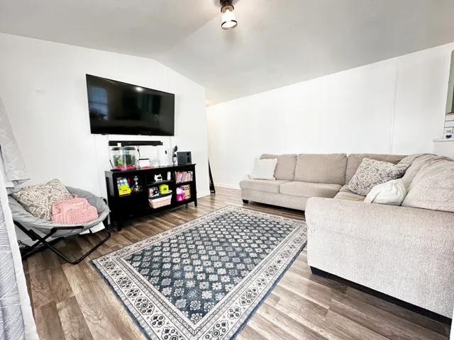 Bright living area featuring wood-finish flooring, white paneled walls, and a recessed ceiling light fixture