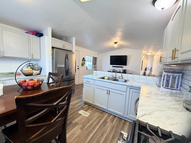 Kitchen featuring white cabinetry with gold-finish hardware, wood-finish flooring, subway tile backsplash, and a double basin sink