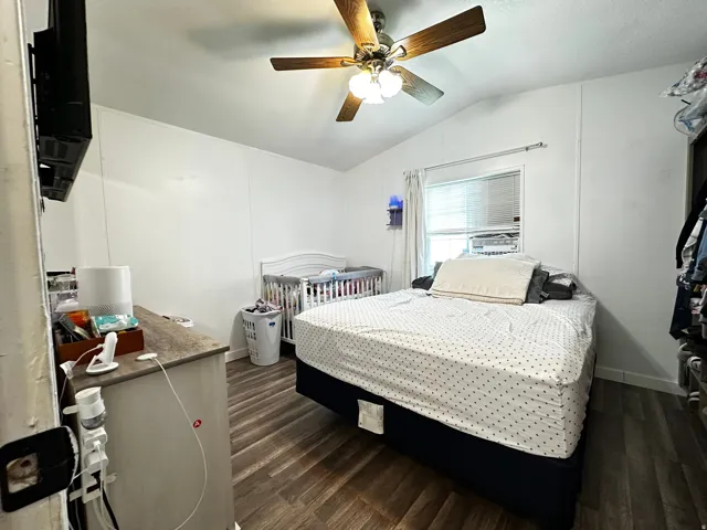 Bedroom featuring dark wood-style flooring, lofted ceiling, and a ceiling fan
