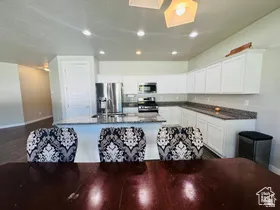 Kitchen with stainless steel appliances, a center island with sink, white cabinetry, recessed lighting, and dark wood-style floors