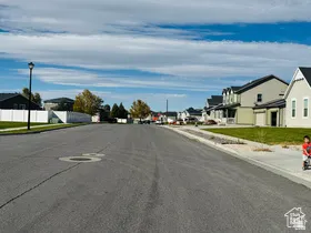 View of asphalt street with sidewalks, a residential view, curbs, and street lighting