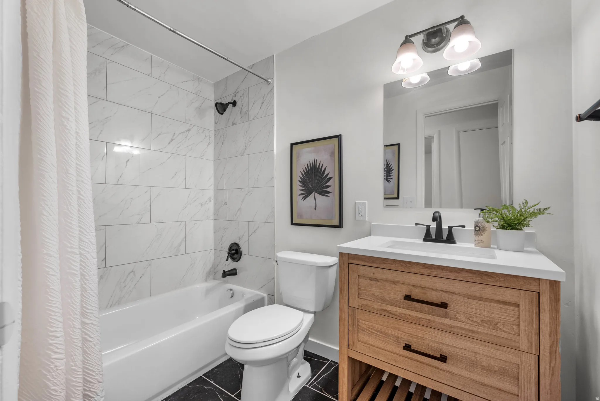 Bathroom featuring shower / bath combination with curtain, vanity, and dark tile patterned flooring