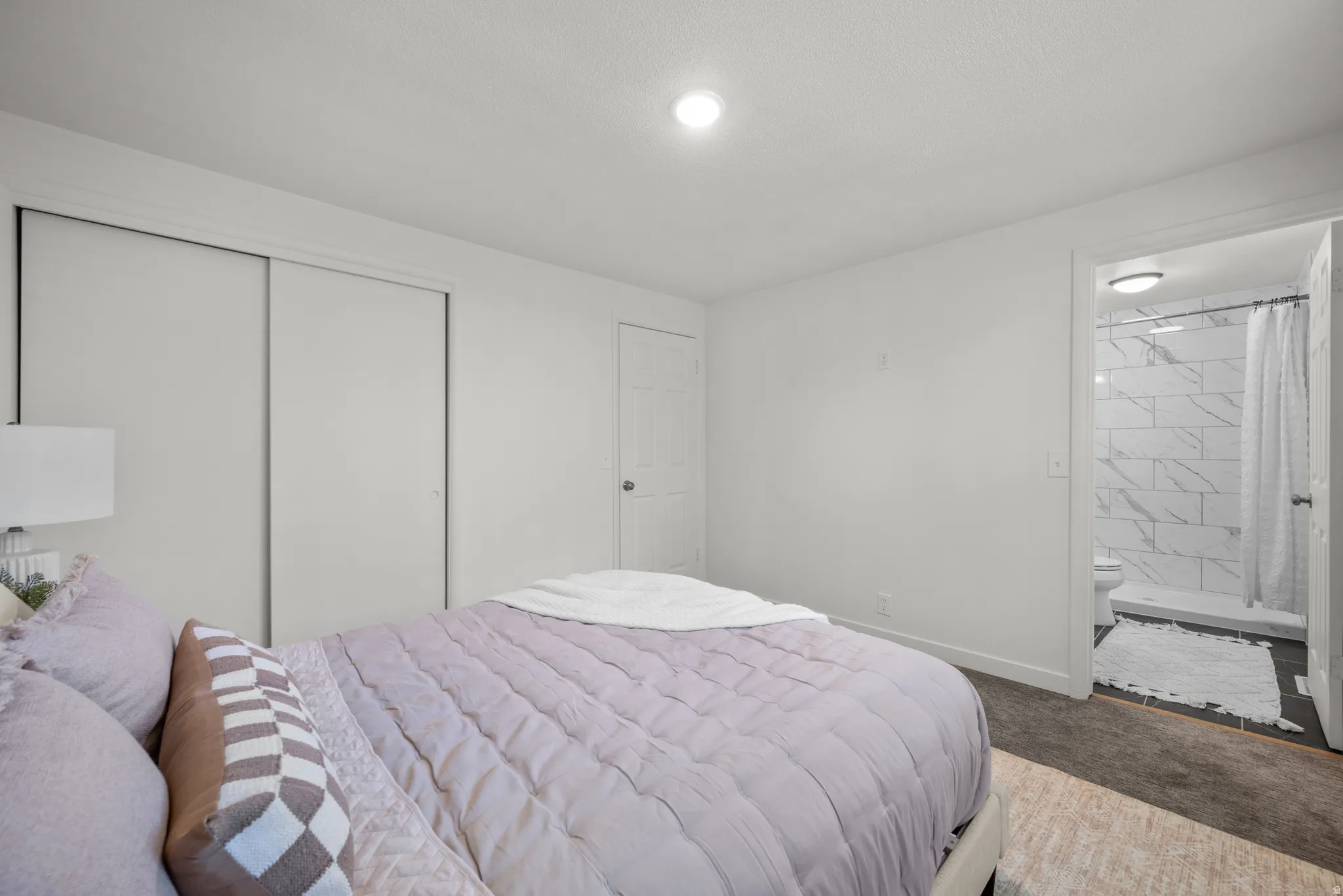 Bedroom featuring a closet, carpet flooring, and ensuite bath