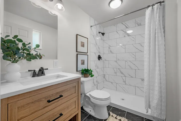 Full bath with vanity, a stall shower, and light marble finish floors