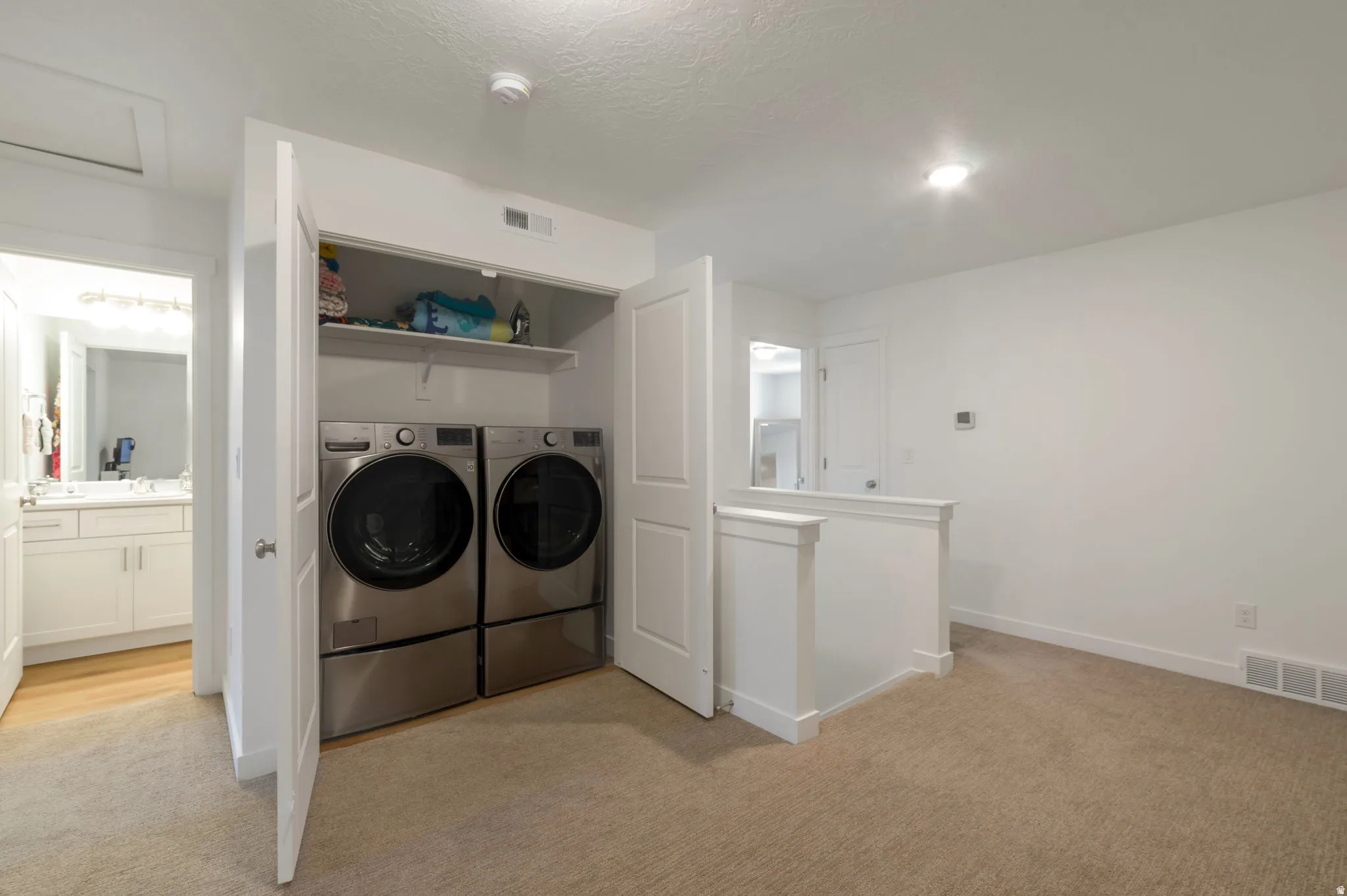 Laundry area featuring light carpet and washer and dryer