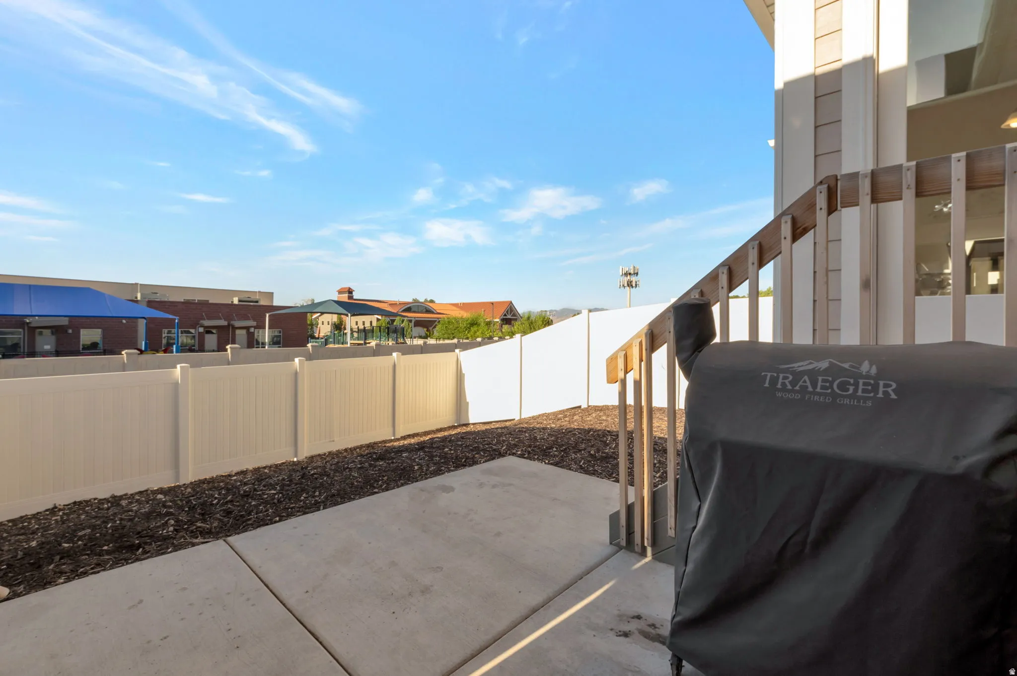 Fenced backyard with area for grilling and a patio