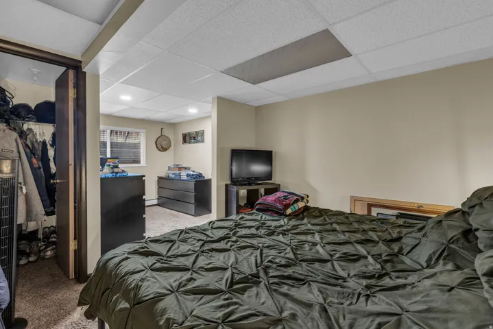 Bedroom with carpet floors, a spacious closet, and a drop ceiling