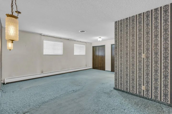 Unfurnished room featuring a baseboard heating unit, carpet flooring, and a textured ceiling