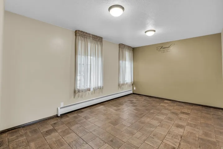 Empty room featuring a baseboard heating unit, parquet flooring, and a textured ceiling