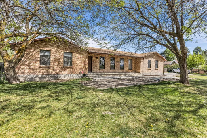 Back of property with a lawn, brick siding, and a patio area