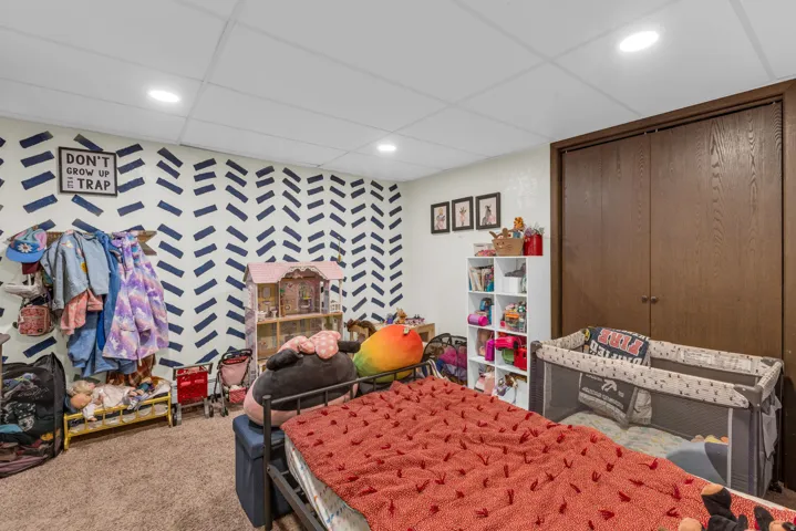 Carpeted bedroom featuring a closet, wallpapered walls, and an accent wall