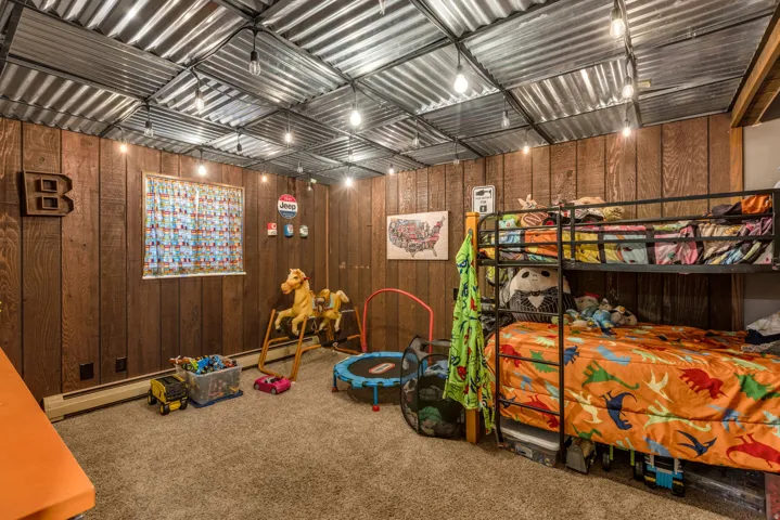 Bedroom with wooden walls, carpet floors, and a baseboard heating unit