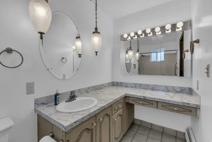 Full bath with vanity, a baseboard radiator, a shower, and light tile patterned floors