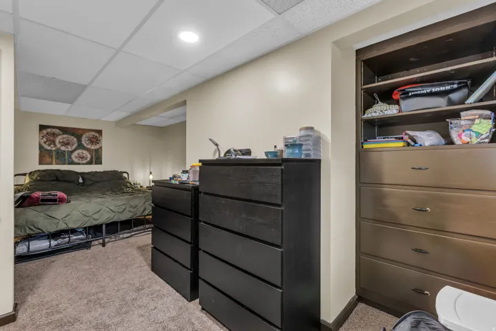 Bedroom with a drop ceiling and light carpet