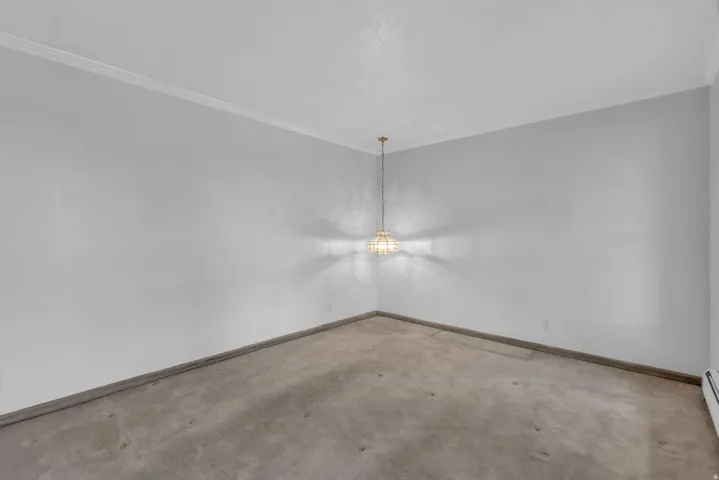 Carpeted spare room with ornamental molding and baseboards