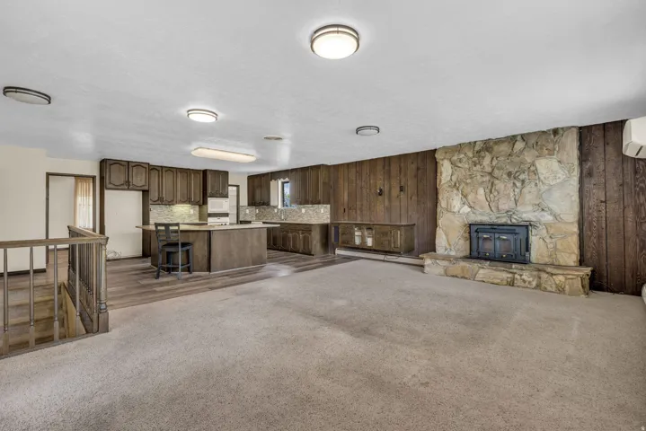 Unfurnished living room with dark carpet, baseboard heating, and wood walls